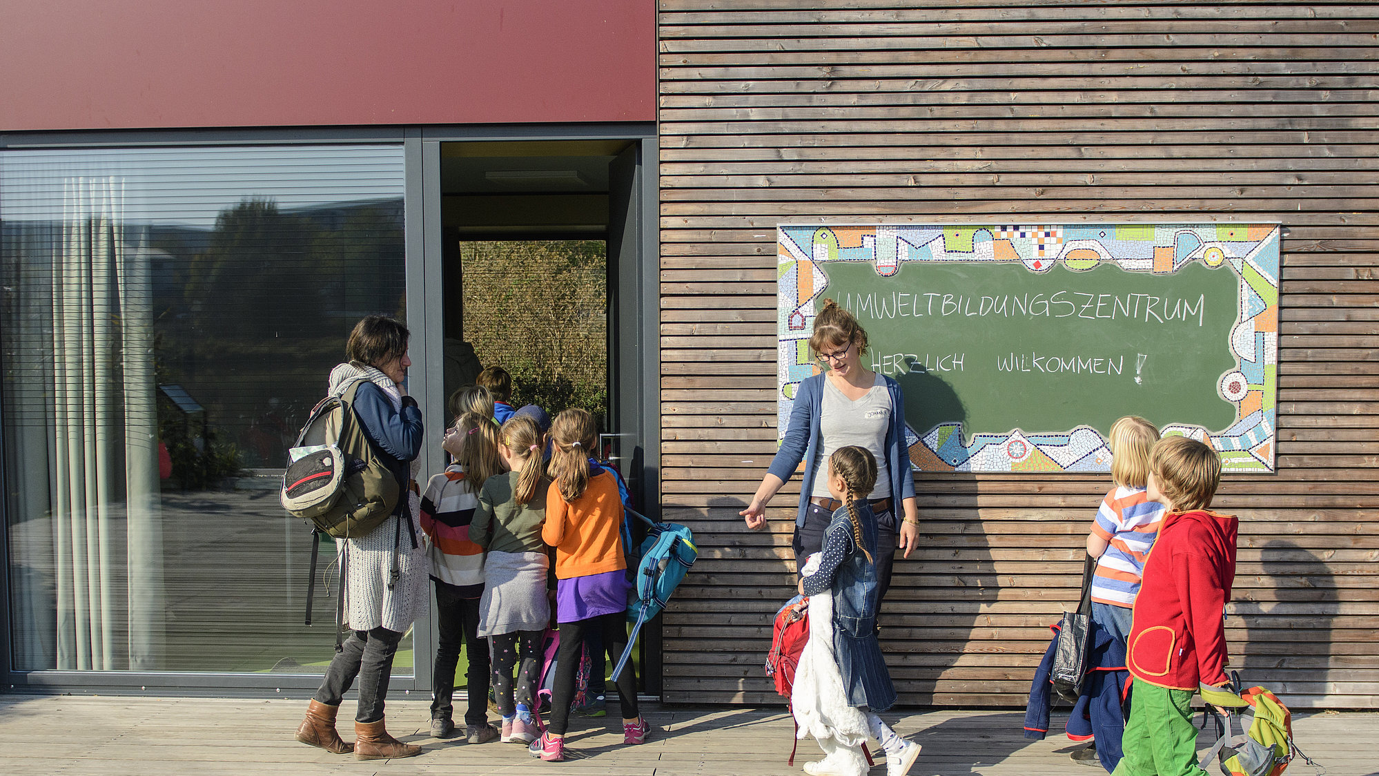 Eine Gruppe Kinder läuft in das mit Holz verkleidete Umweltbildungszentrum im Kienbergpark rein